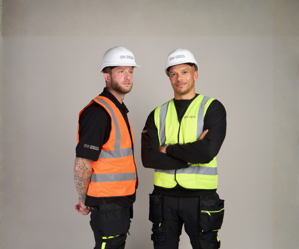 two men wearing branded hi-vis vests in orange and yellow while also wearing hard hats.
