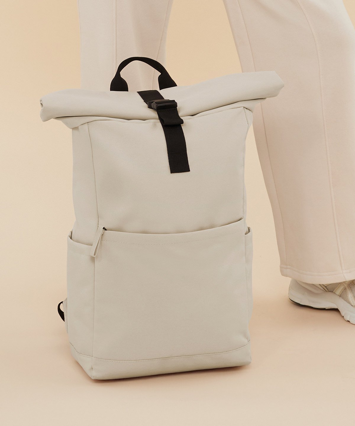 Premium Recycled Roll Top Backpack 5 a cream bag resting on a leg, while being on a floor